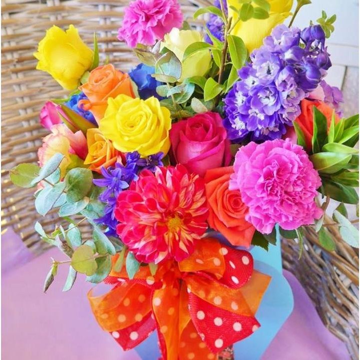 Jellybean. A vibrant and funky arrangement of bright seasonal flowers arranged in our new modern style.  Loose formed but carefully constructed to envoke a "just picked from the garden" look.  Delivered in our new bloombox and finished with a big bright bow.